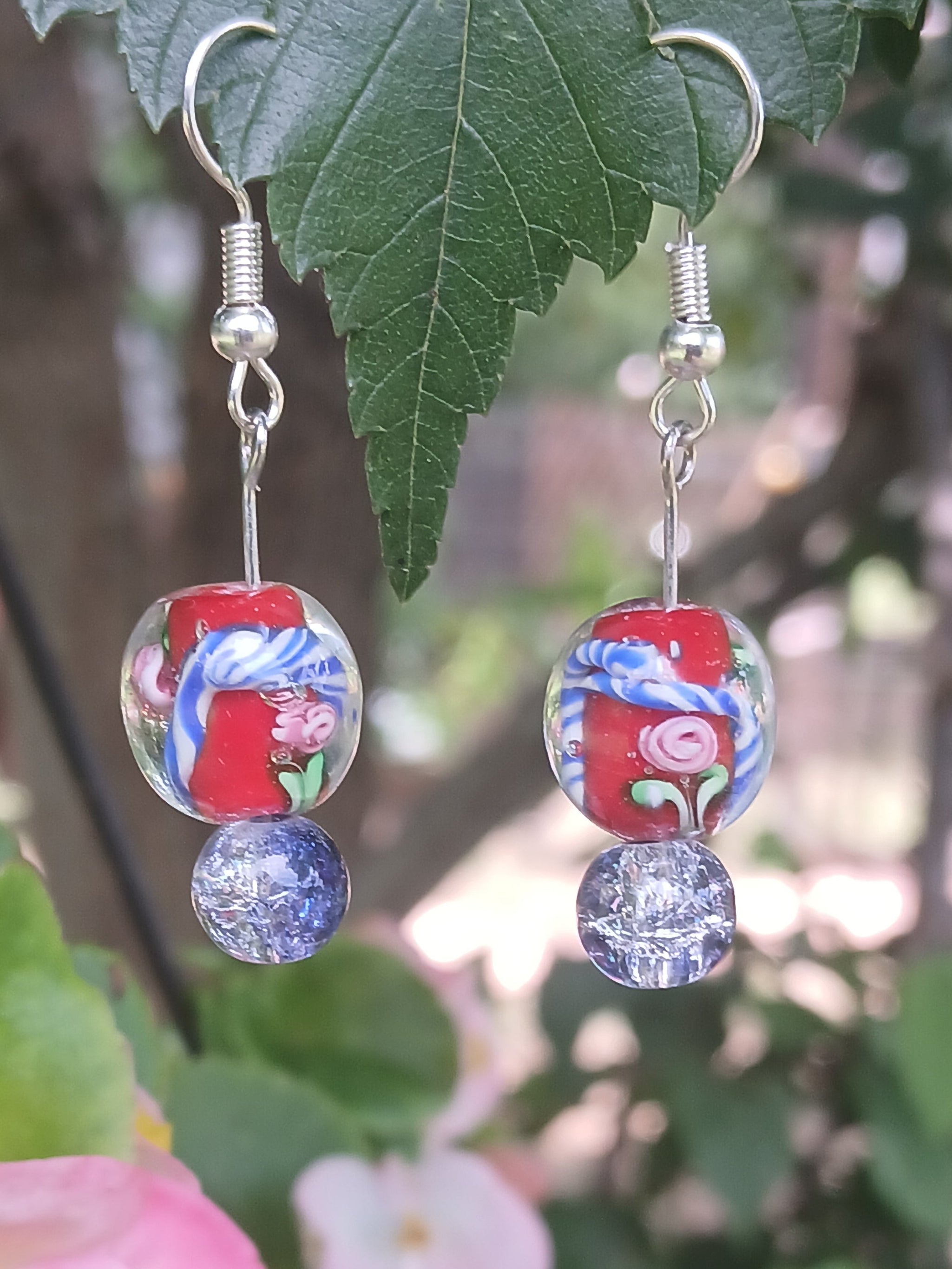 Pair of earrings with floral design on a green leafy background
