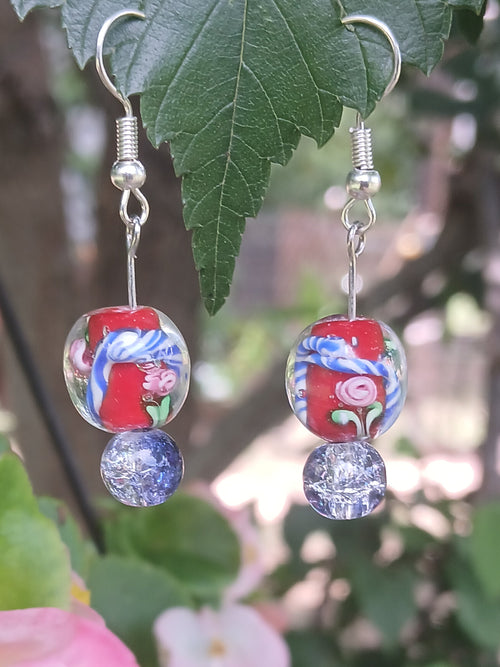 Pair of earrings with floral design on a green leafy background
