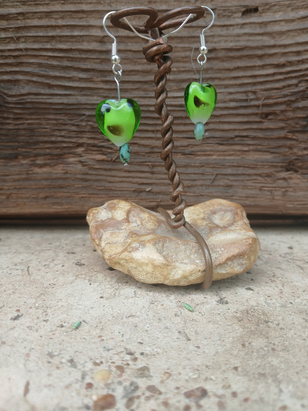 Fishing lure with green body and brown handle on a textured surface