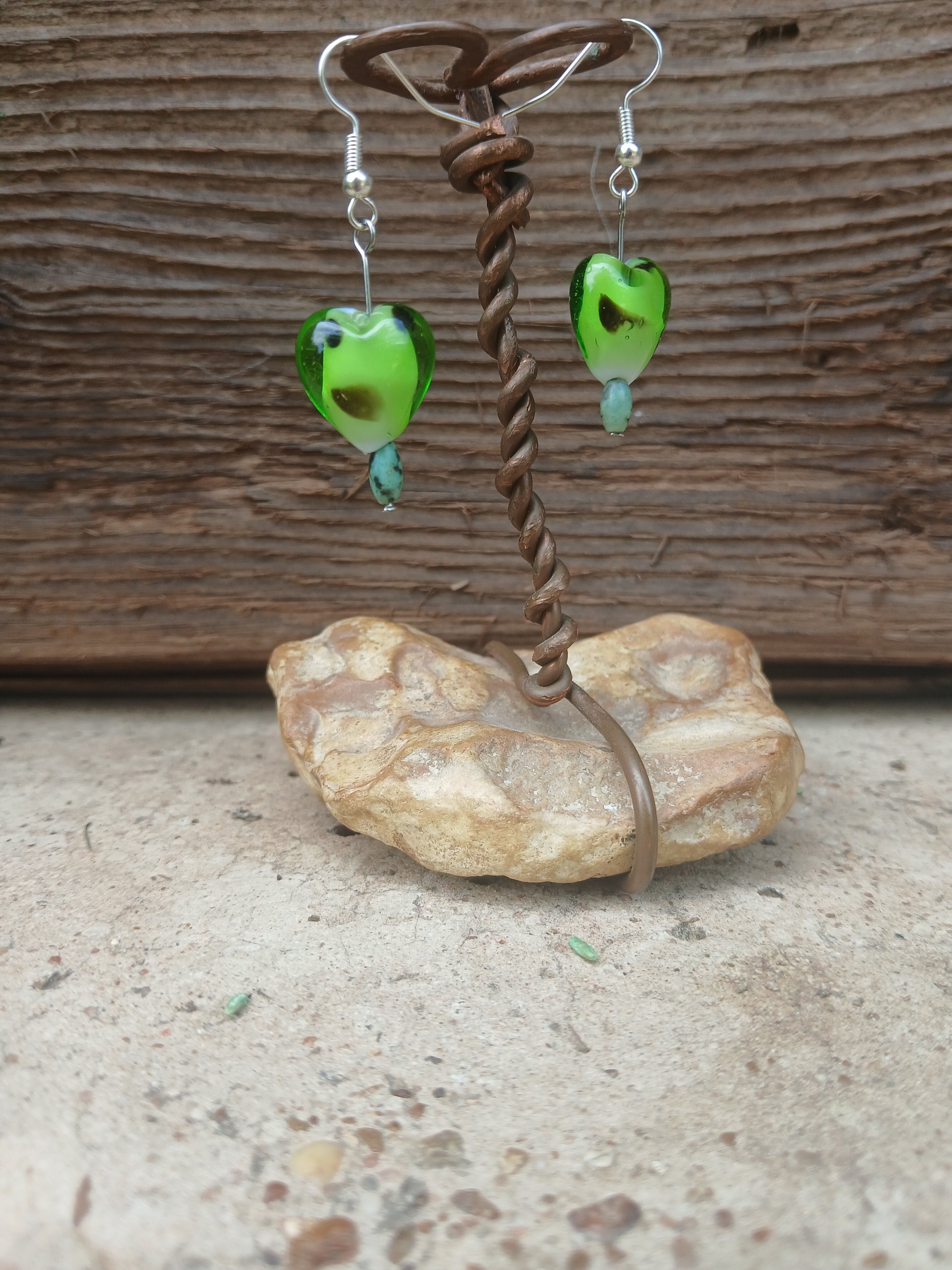 Fishing lure with green body and brown handle on a textured surface