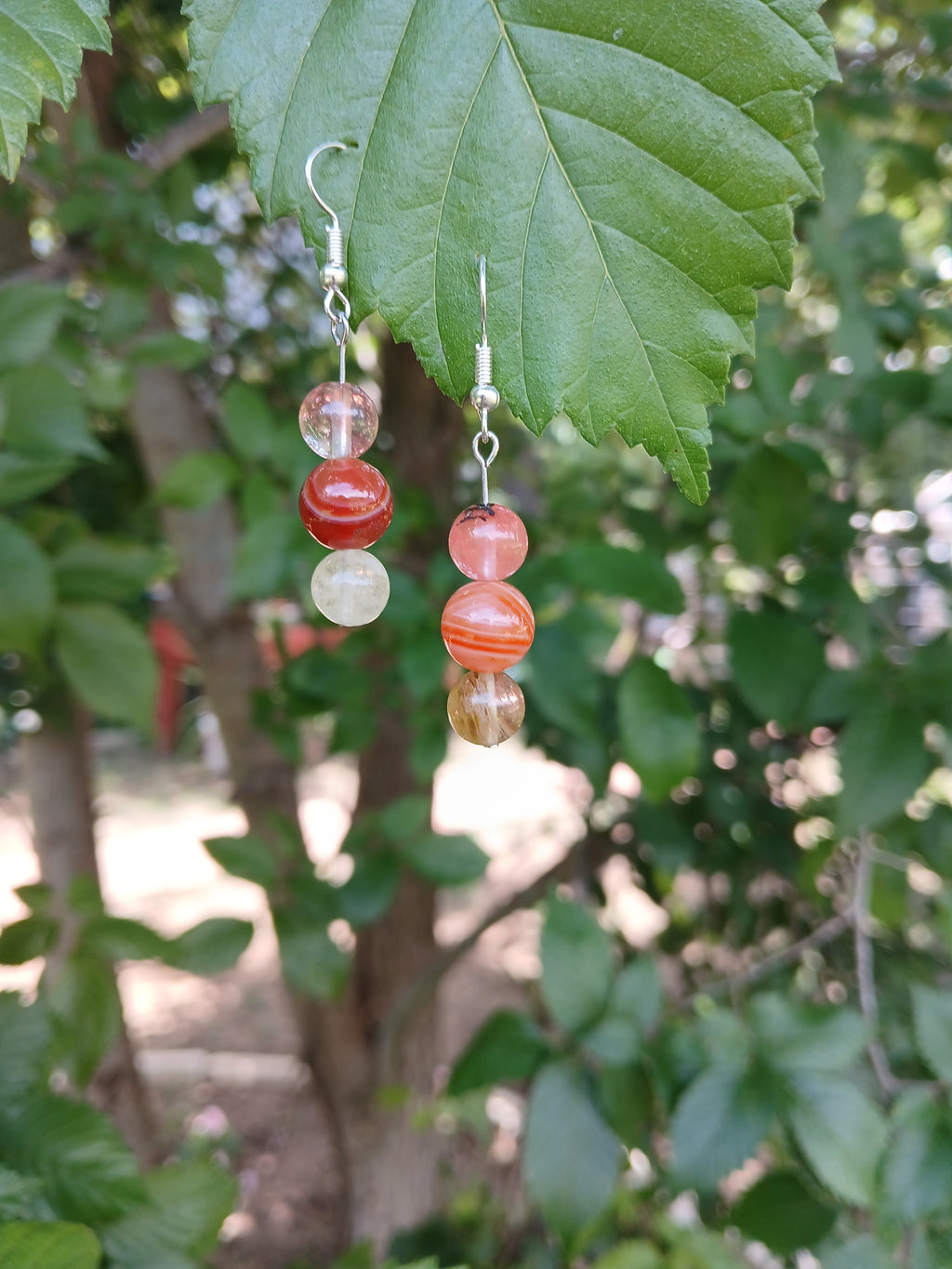 Beaded earring on a leaf with a blurred green foliage background