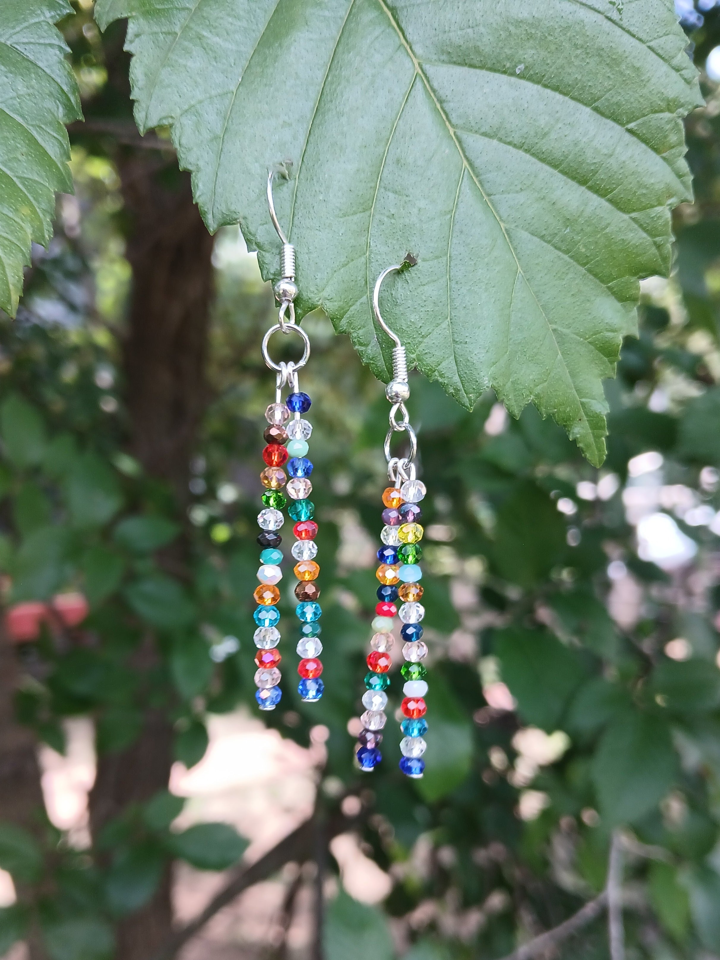 Colorful beaded earrings on a leaf with a natural background