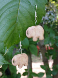Elephant-shaped earrings hanging from a green leaf