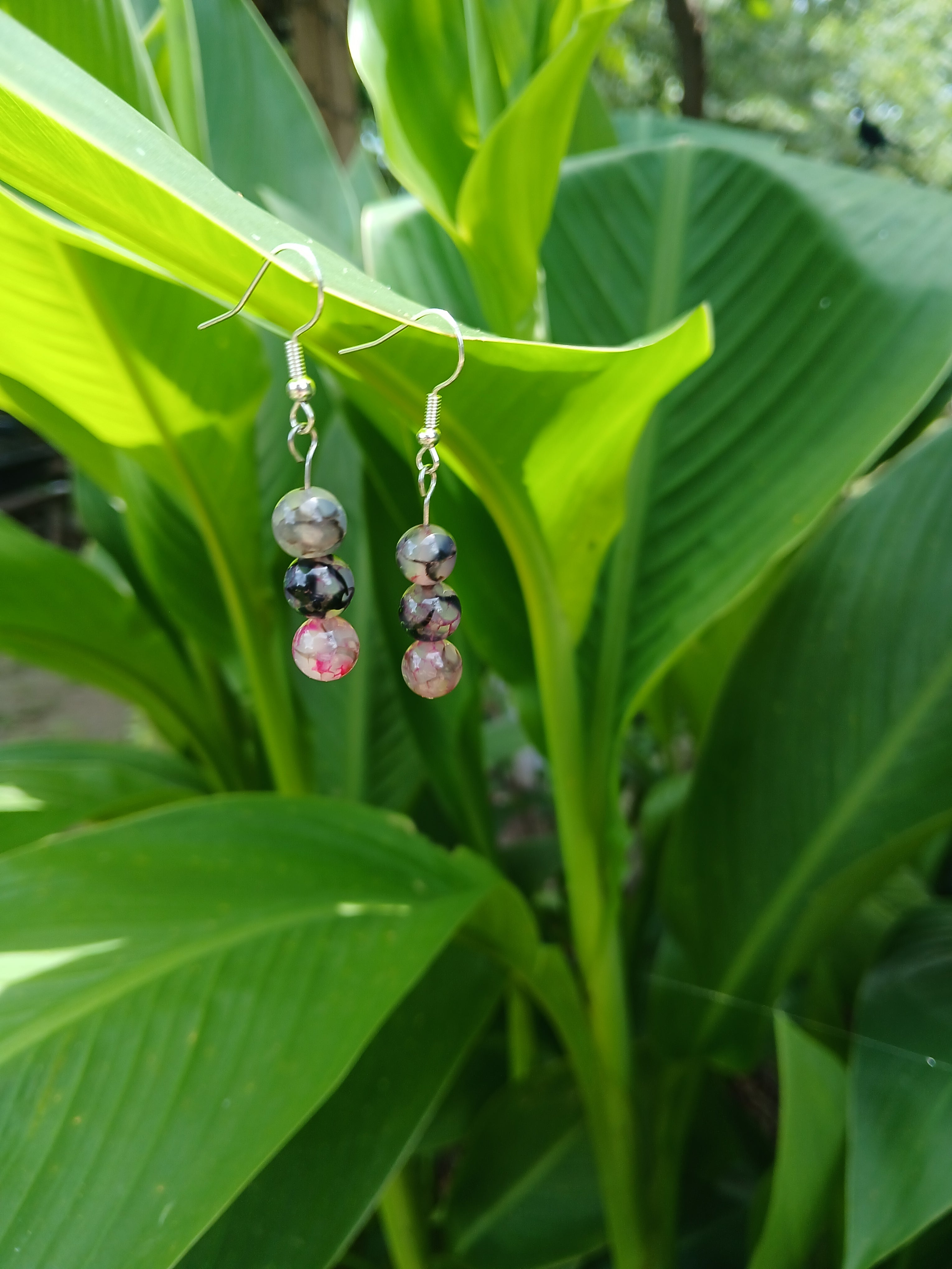 Pair of earrings with multicolored beads on a green leaf background