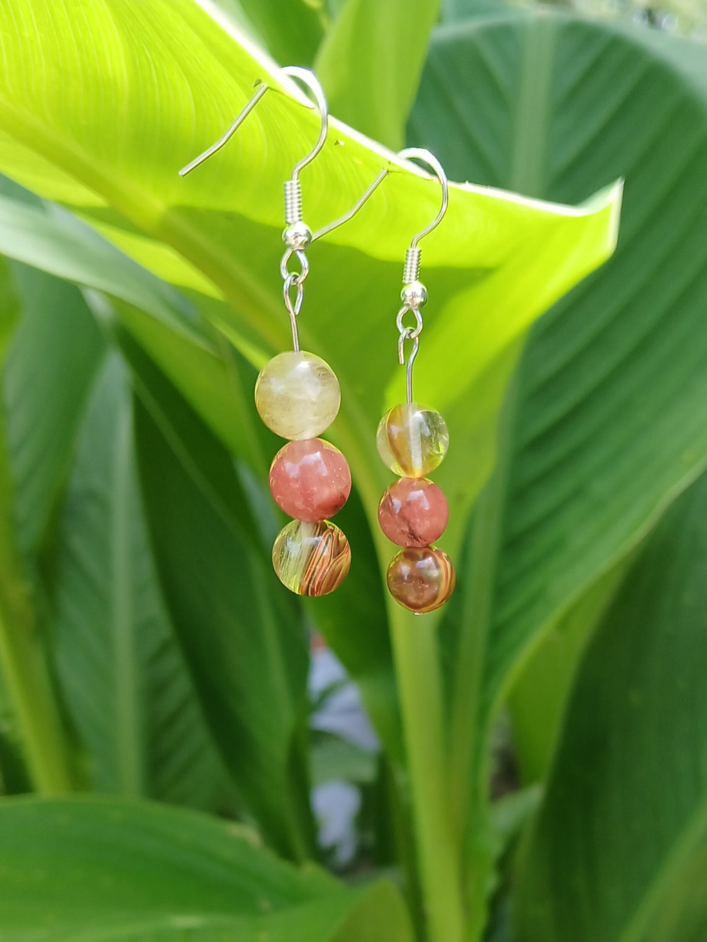 Earrings with colorful beads on a green leaf background
