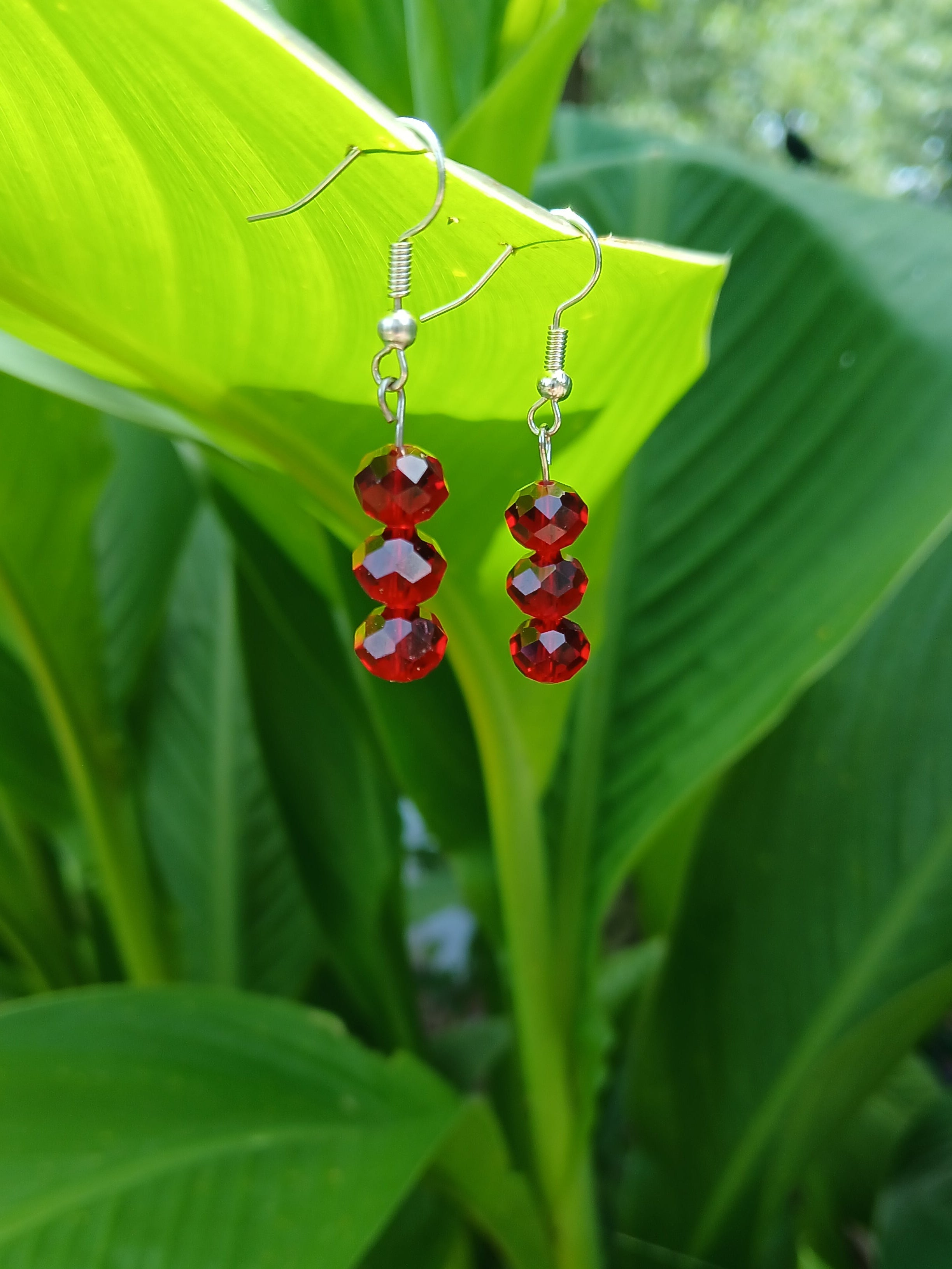 Red beaded earrings on a green leaf