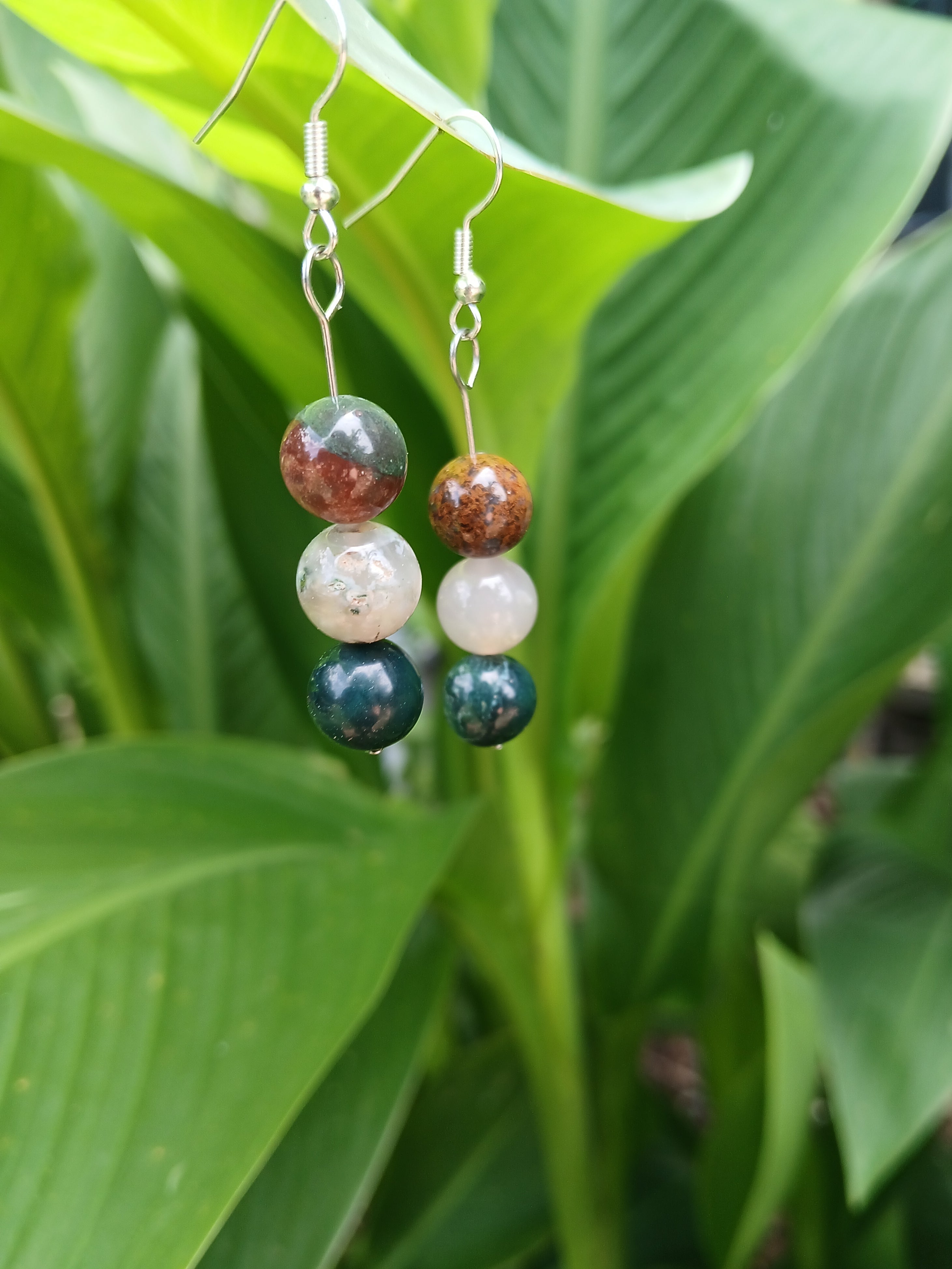 Beaded earrings with multicolored beads on a green leaf background