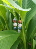Pair of beaded earrings on a green leafy background