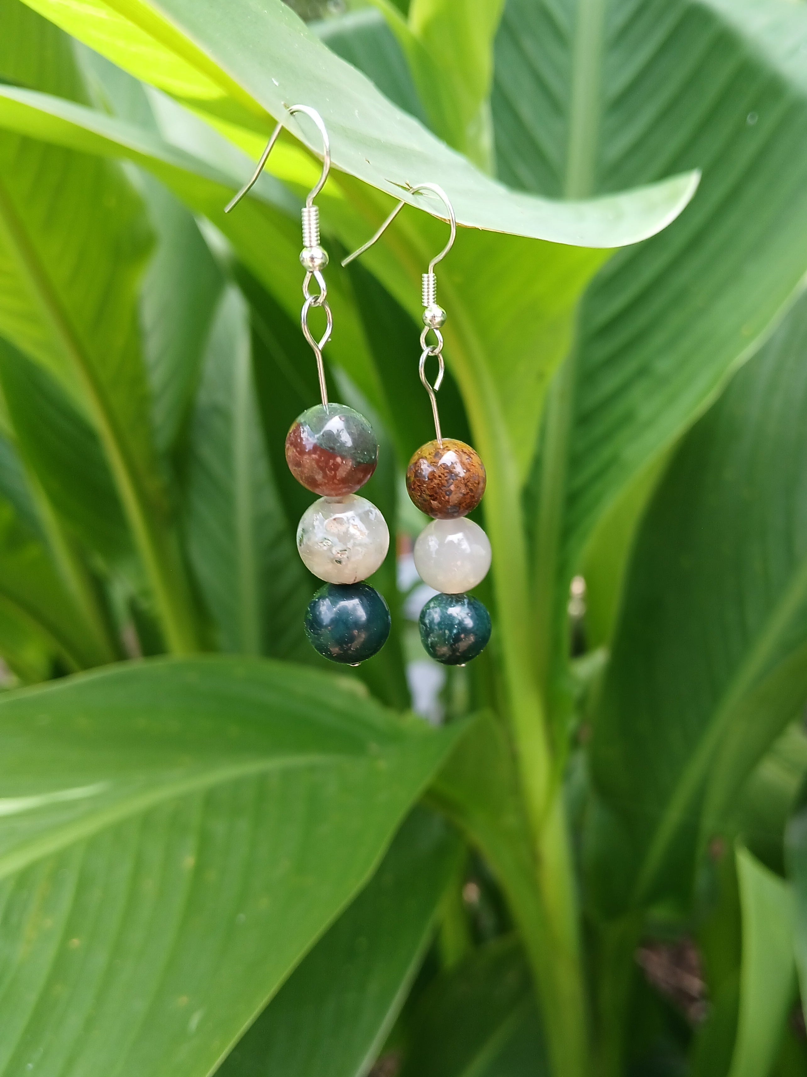 Pair of beaded earrings on a green leafy background