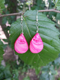 Pink earrings on a green leaf with a natural background