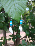 Pair of earrings with blue and white beads on a leafy background