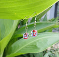 Pair of earrings with floral design on a green leaf