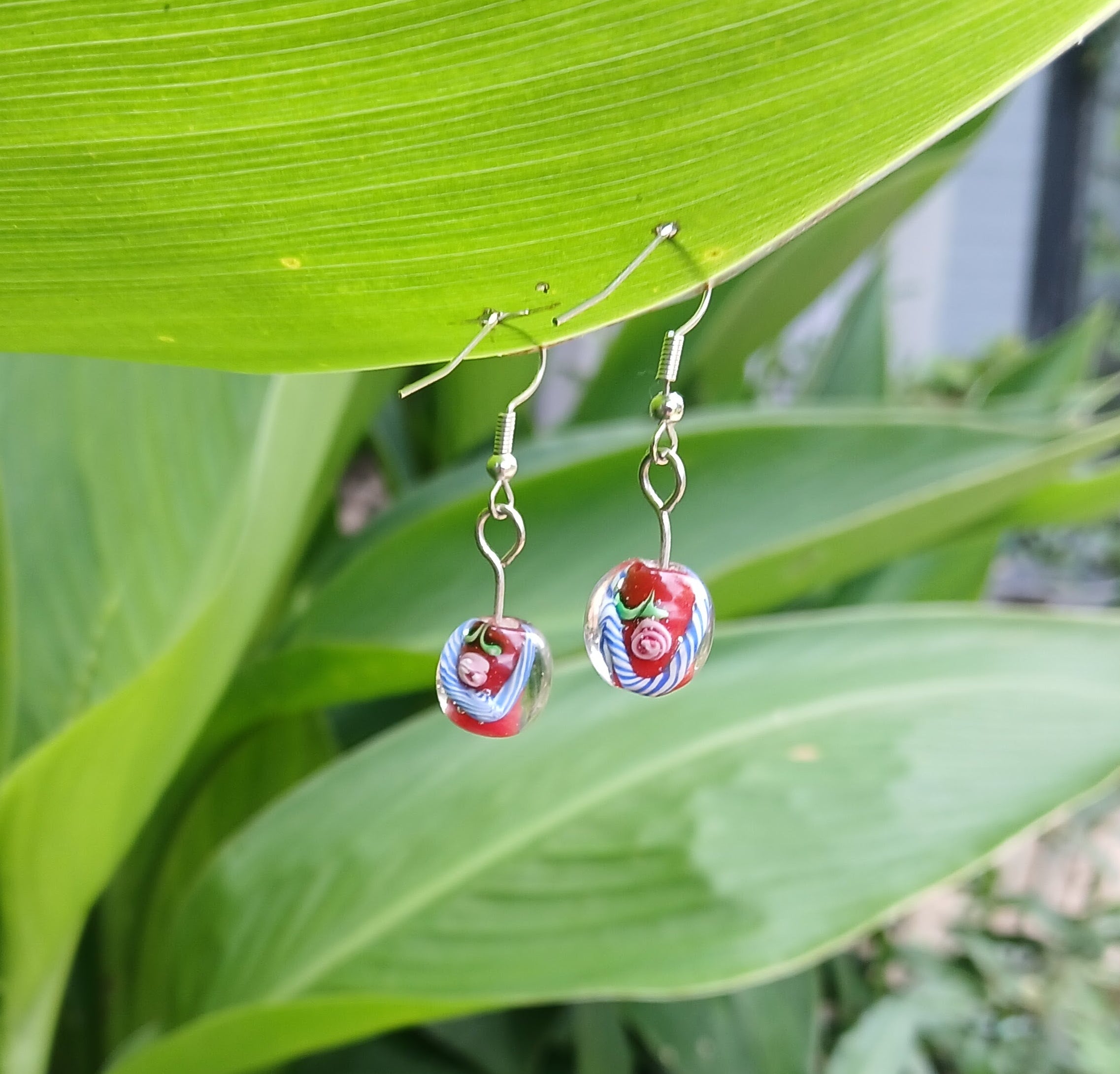 Pair of earrings with floral design on a green leaf